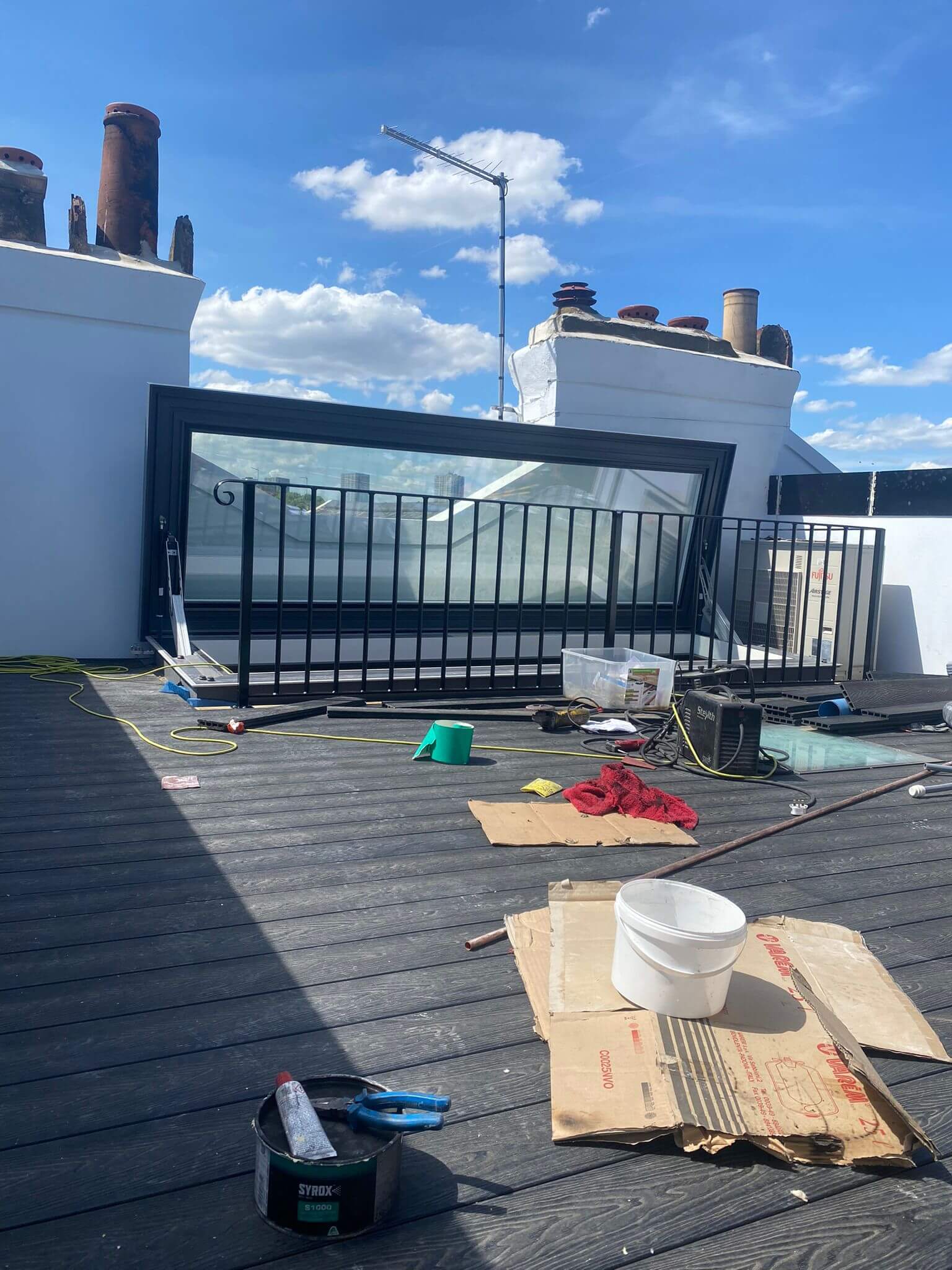 Rooftop balcony installation in progress with black metal railings on wooden deck