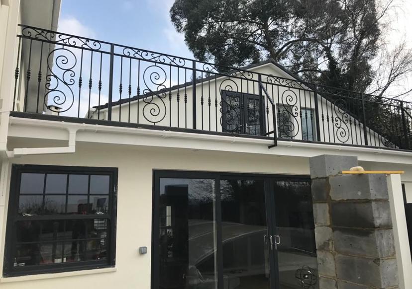 Completed elegant balcony railings with ornate scrollwork on modern white building