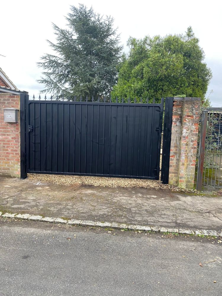 Large sliding gate with vertical black slats spanning driveway