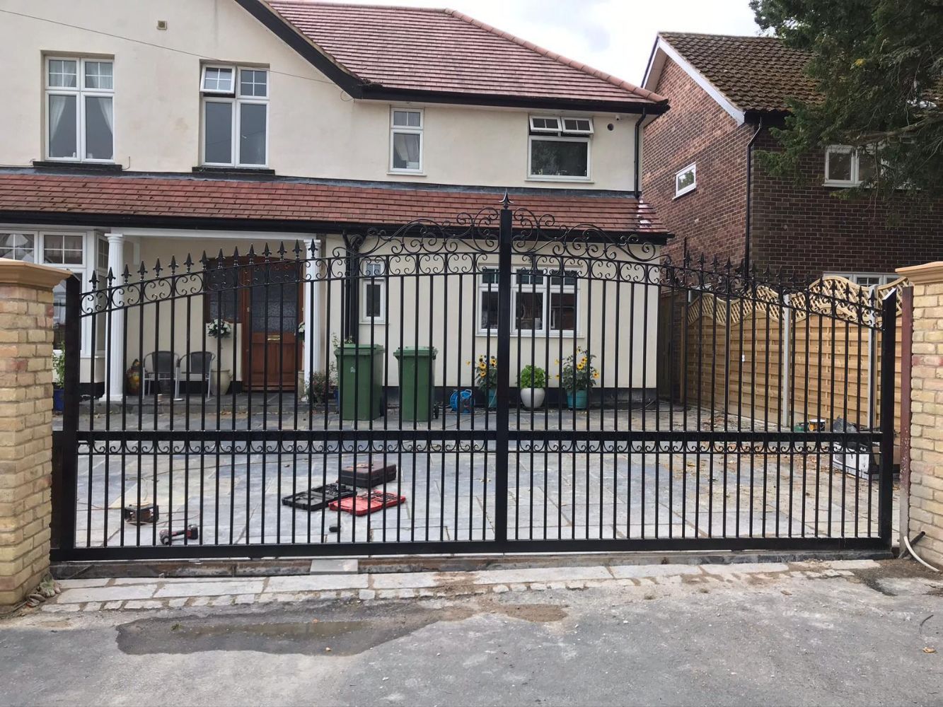 Ornate black wrought iron driveway gates with elaborate decorative scrollwork and spear-point tops