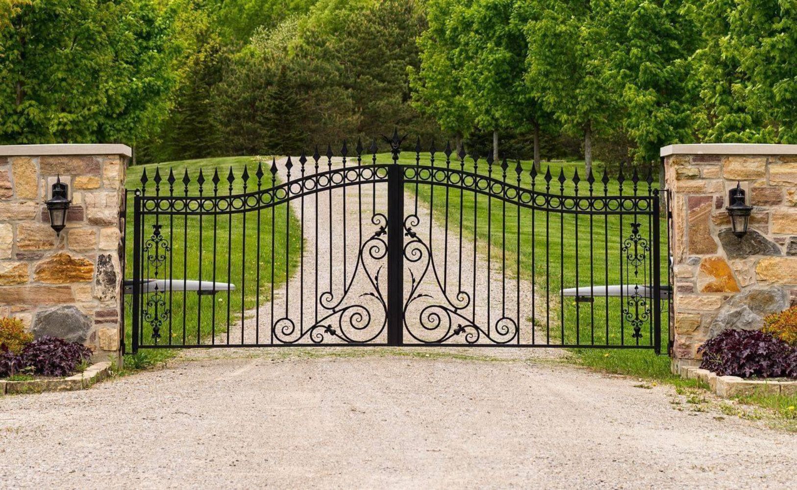 Grand estate-style entrance gates with sophisticated scrollwork medallions and stone pillars