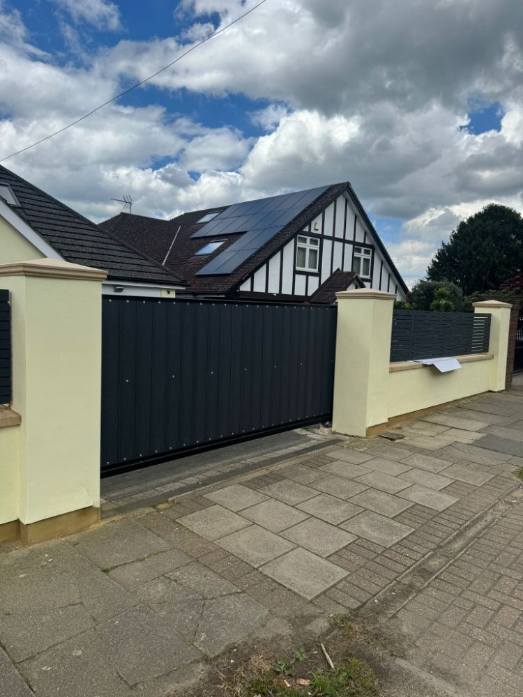 Sliding gate with vertical slats between cream pillars
