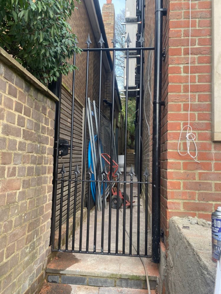Simple black vertical bar gate in narrow alleyway