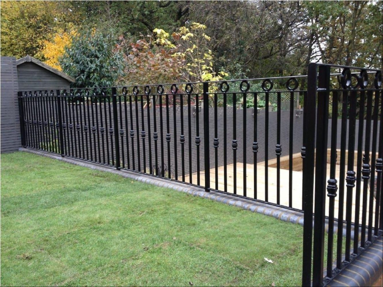 Long decorative black metal boundary railing with vertical bars and circular ring details