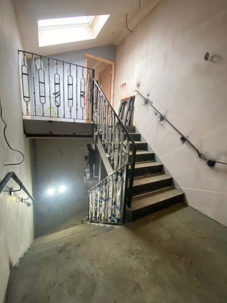 Interior staircase with black metal railings featuring decorative oval patterns and wooden treads