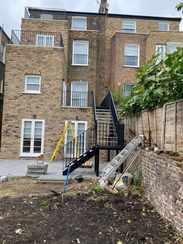 Black metal external staircase under construction in residential courtyard