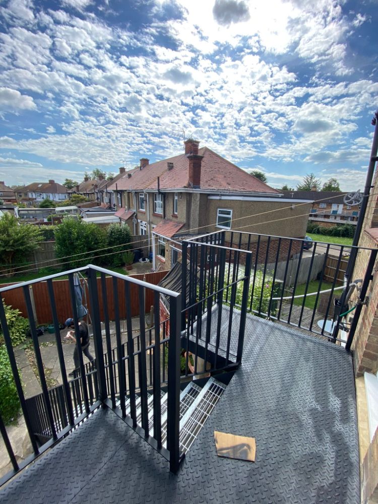 Completed black metal fire escape staircase with perforated treads viewed from above