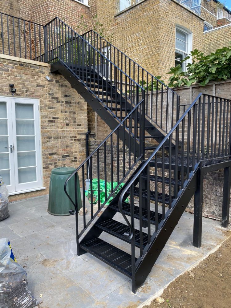 L-shaped black metal staircase with vertical bar railings in residential setting