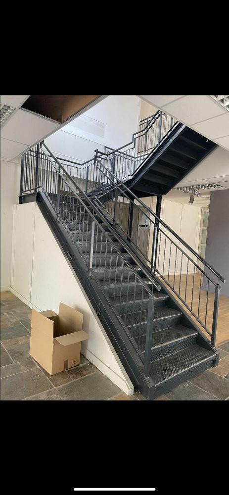 Interior commercial staircase with black metal frame and perforated treads